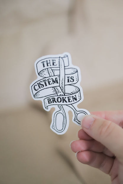 The Cistem is Broken Sticker – Ribbon & Scissors Design (4")